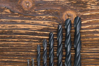 Yanmış ahşap arka planda metal için matkaplar, yazıtlar için yer bırakılmış.