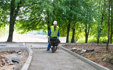 Mavi üniformalı bir işçi, yol boyunca bir tramvay taşıyor.