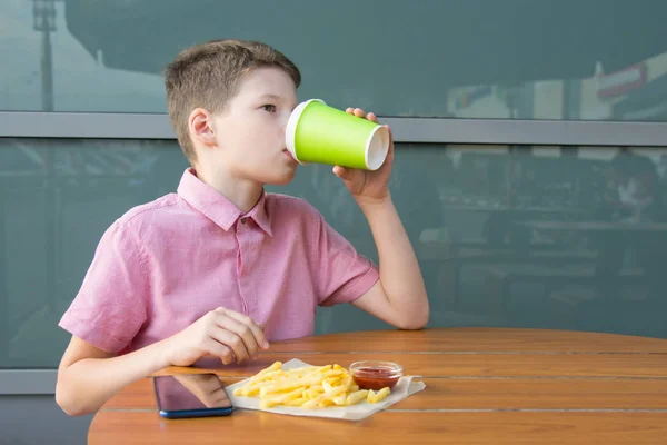 Niño Está Sentado Mesa Bebiendo Una Bebida Vaso Desechable Comiendo — Foto de Stock