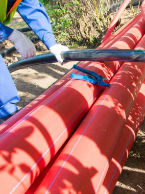 İşçiler beyaz eldivenler veriyor, makasla kesmek için plastik bir boru tutuyorlar.