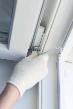 Koruyucu eldivenli el işçisi, plastik pencere anahtarını ayarlar, yakın plan.