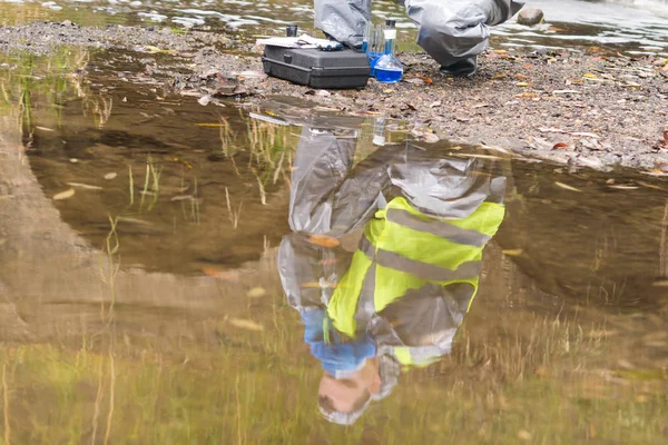 in water reflection of a man in a protective suit and mask