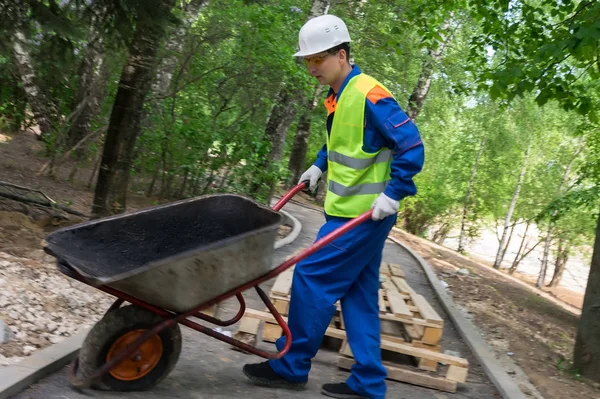 Pracownik Kasku Niesie Pusty Wózek Niedokończonych Drogach — Zdjęcie stockowe