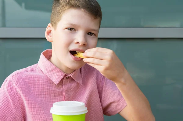 熱いお茶を飲んでフライドポテトを食べる少年の正面図 — ストック写真