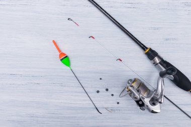 Açık gri bir arka planda, olta kamışı ve yüzer