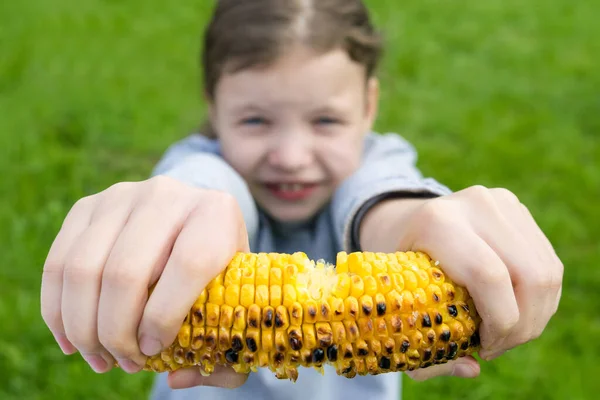 Flicka Utomhus Sitter Gräs Och Visar Grillad Majskolv — Stockfoto