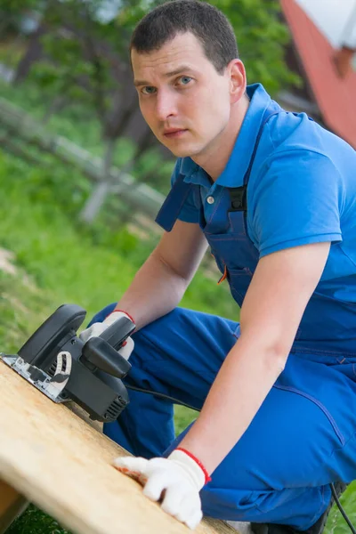Trabajador Uniforme Azul Corta Una Tabla Madera Con Una Sierra — Foto de Stock