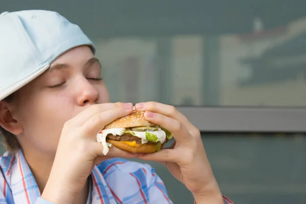 Chica Una Gorra Sentado Mesa Comiendo Comida Rápida Hamburguesa Primer — Foto de Stock