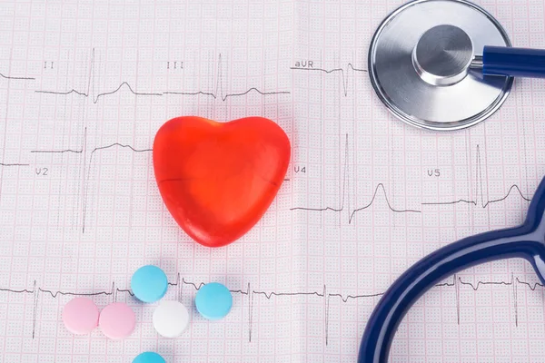 on the background of a cardiogram, artificial heart, phonendoscope and multi-colored pills, close-up