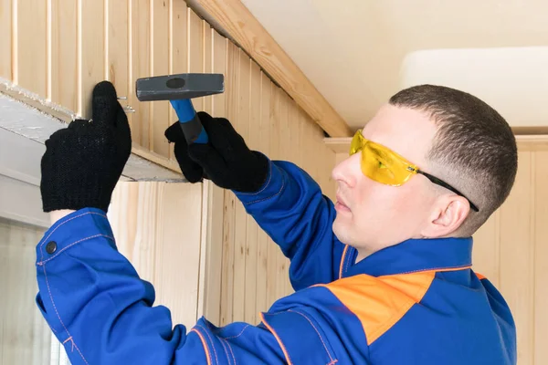 Ein Arbeiter Blauer Spezialkleidung Befestigt Eine Holzplatte Mit Nägeln Und — Stockfoto