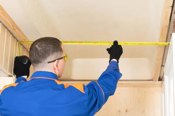 Worker in blue special clothes measures flow using yellow tape measure — Stock Image Worker Blue Special Clothes Measures Flow Using Yellow Tape Measure Royalty Free Stock Photos