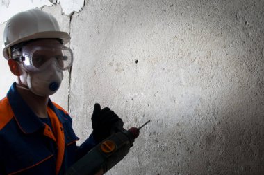 Koruyucu giysiler, maske ve başlık takan işçiler beton duvarları sökmekle meşgul, matkap, yazıt için bir yer var.