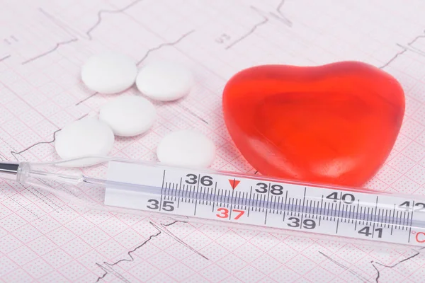 on the background of a cardiogram, a heart, pills and a thermometer are located