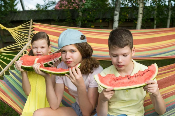 Två Flickor Och Pojke Sitter Hängmatta Och Äter Röd Vattenmelon — Stockfoto