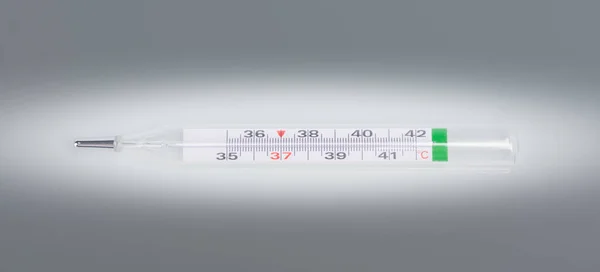 glass thermometer, for measuring body temperature, against a background of blackout, close-up