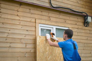 İşçi, başka bir adrese taşınırken ahşaptan yapılmış koruyucu bir kalkan ile evin penceresini tahta kapadı.