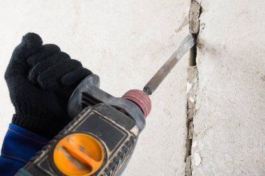 Elleri kaya matkabını tutuyor beton duvarda çalışıyor, yakın plan.