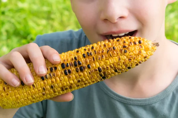 Little Boy Bites Fried Yellow Ear Corn Sitting Green Grass — Stock Photo, Image