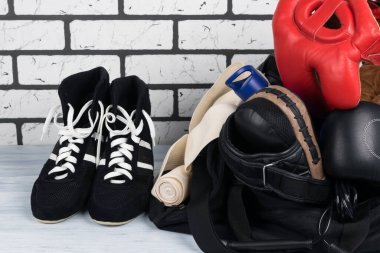Spor çantasının yanında antrenman için bir şeyler ve yanında da tuğla duvara karşı güreş ayakkabıları var.