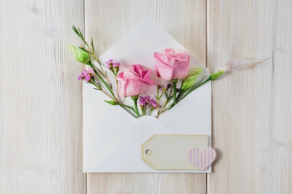 Ahşap arka plan üzerinde çiçekler olan zarf.