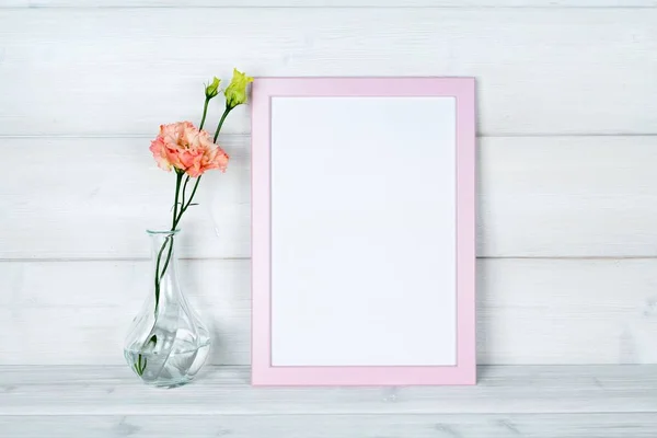 Çiçek vazo ve ahşap arka plan üzerinde bir fotoğraf çerçevesi.