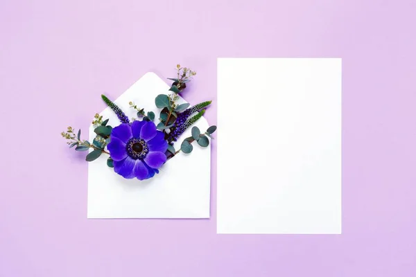 Πολύχρωμα ανοιξιάτικα λουλούδια στο φάκελο και λευκό φύλλο σε μοβ φόντο. — Φωτογραφία Αρχείου