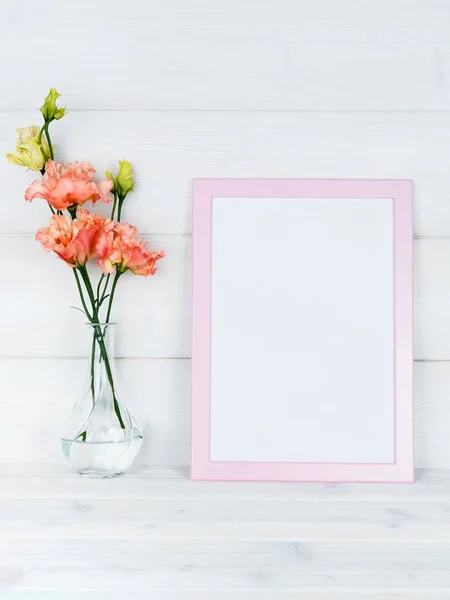 Çiçek vazo ve ahşap arka plan üzerinde bir fotoğraf çerçevesi.