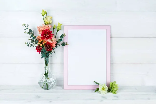 Çiçek vazo ve ahşap arka plan üzerinde bir fotoğraf çerçevesi.