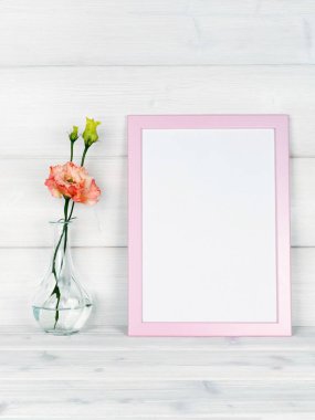 Çiçek vazo ve ahşap arka plan üzerinde bir fotoğraf çerçevesi.