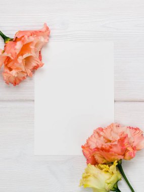 Pembe çiçekler ve ahşap arka plan üzerinde beyaz sayfa.