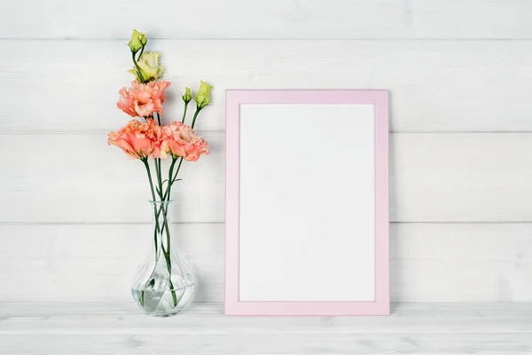 Çiçek vazo ve ahşap arka plan üzerinde bir fotoğraf çerçevesi.