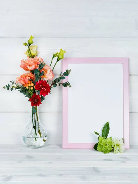 Çiçek vazo ve ahşap arka plan üzerinde bir fotoğraf çerçevesi.