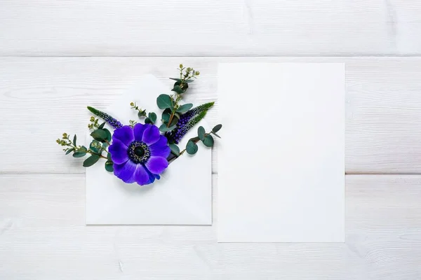 Zarf ve beyaz sayfa ahşap zemin üzerine mavi çiçek.