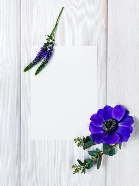 Блакитні квіти та білий аркуш на дерев'яному фоні . — стокове фото