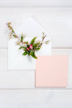 Zarf ve pembe sayfasında ahşap arka plan üzerinde renkli bahar çiçekleri.