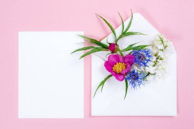 Zarf ve beyaz sayfa pembe bir arka plan üzerinde renkli yaz çiçek.