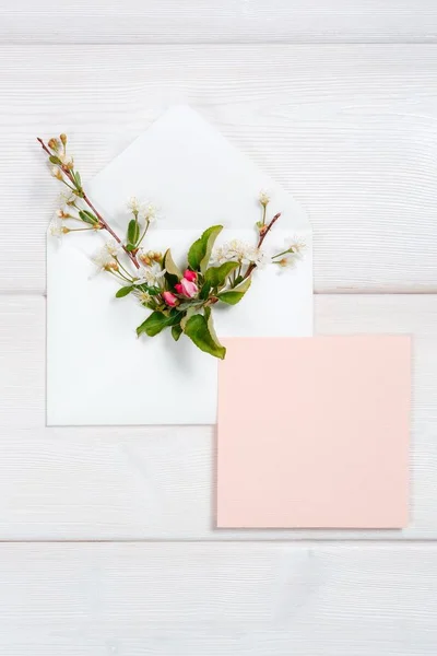 Барвисті весняні квіти в конверті і рожевий лист на дерев'яному фоні . — стокове фото