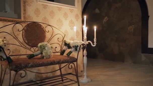 Bouquets em um banco nos lados que acenderam velas em castiçais — Vídeo de Stock