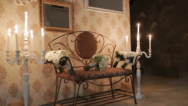 Bouquets sur un banc sur fond de décorations de mariage. Sur les côtés des bougies en chandeliers — Video