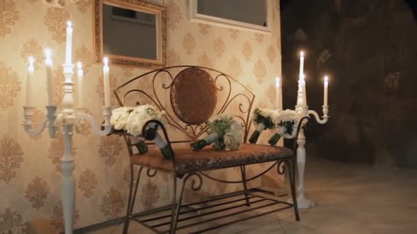 Bouquets on a bench on the sides which lit candles in candlesticks — Stock Video