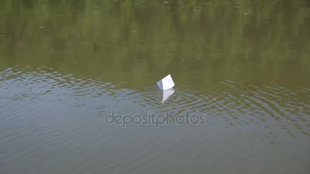 Бумажная лодка, плавающая по воде — стоковое видео