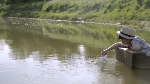 El pobre chico en el barco, jugando con el barco de papel — Vídeos de Stock