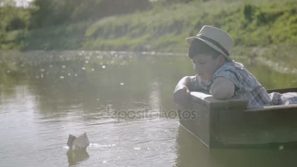 Junge schickt Segelschiff aus der Zeitung, während er im Boot sitzt — Stockvideo