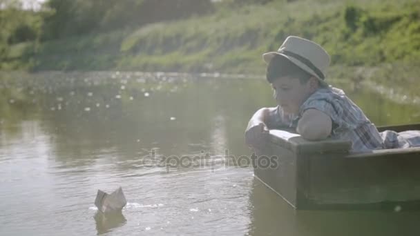 Anak laki-laki mengirim kapal berlayar dari koran sambil duduk di perahu — Stok Video