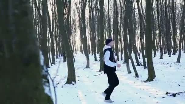 Pohledný chlap běžící v lese v zimním období. Únava po běhání — Stock video