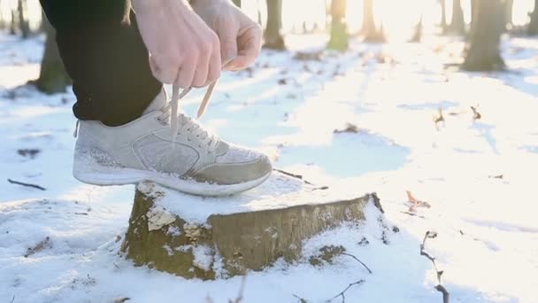 A sportoló odakötő cipőfűzők-cipők. Vértes runner készül kint a parkban, télen. Hó és nap — Stock videók