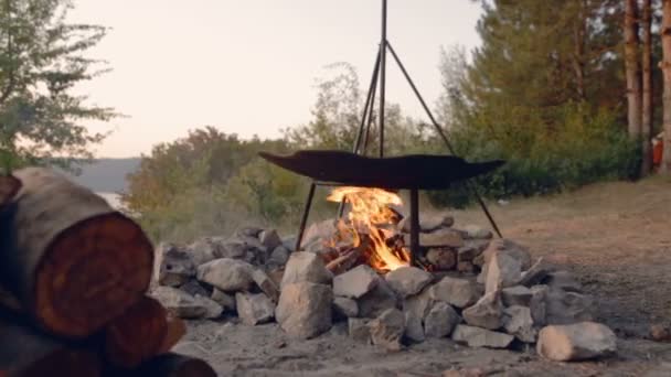 DOLLY MOTION: Cocinar dos platos en llamas. Comida en la campaña. Viaje a los bosques salvajes a la vida silvestre. Viajes románticos. Ollas turísticas en llamas. Fuego de piedra recubierto — Vídeo de stock