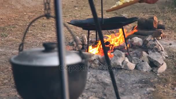 Man throwing a wooden board with potatoes in a large heated pan. Potatoes on disk grill. — Stock Video