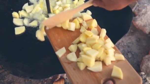 Человек бросает картошку в большую обогреваемую кастрюлю . — стоковое видео
