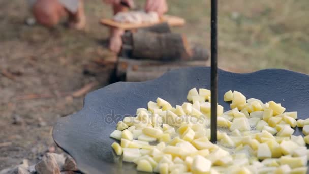 Босоногий мальчик на улице режет жир для приготовления картошки — стоковое видео